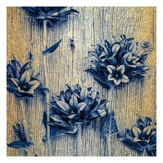 three blue flowers are sitting on a wooden surface