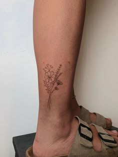 a woman's foot with a small flower tattoo on the lower part of her leg