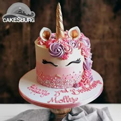 a birthday cake decorated with pink and purple icing, topped with an unicorn's horn