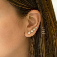 a woman's ear is shown with three small diamond studs