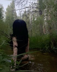 a woman is sitting in the water with her back turned to the camera and looking down