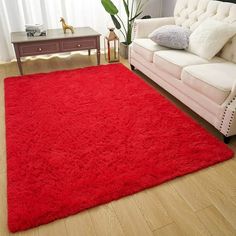 a living room with a white couch and red rug