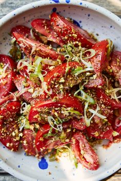 a white bowl filled with sliced tomatoes and sprouts on top of a wooden table