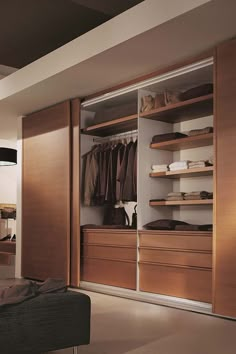 an open closet is shown with clothes and shoes on the shelves, along with a footstool