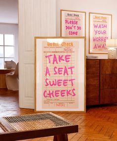 two posters on the wall in a room with wooden flooring and wood table top