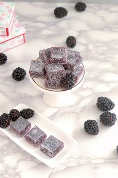 blackberries and raspberry shortbreads on a marble counter top with small white plates