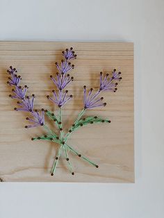 some purple flowers are on a wooden board