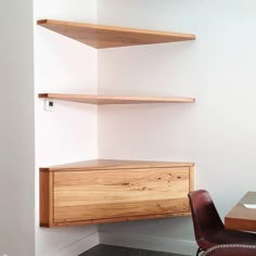 a chair and desk in an office with shelving on the wall above it,