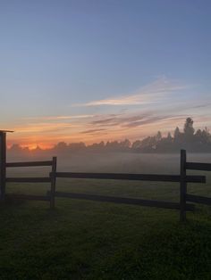 the sun is setting behind a fence on a foggy day