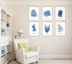 a living room with white furniture and four blue seaweed prints on the wall above it