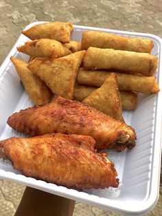 there is a white tray with some food on it that includes chicken wings and fries