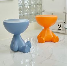 two different colored stools sitting on the floor in front of a mirror and clock