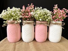 three mason jars with flowers in them on a table