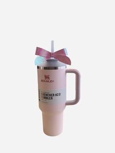 a pink travel mug with a bow on the handle and lid is shown in front of a white background