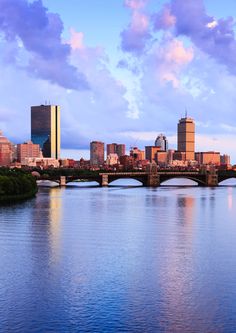 the city skyline is reflected in the still water of the river that runs through it