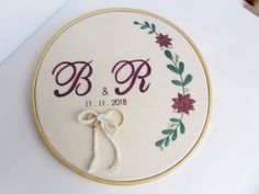 embroidered wedding ring pillow with monogrammed initials and flowers on it, sitting on a table