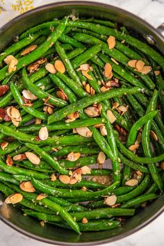 green beans and almonds in a pan on a table with white marble counter top