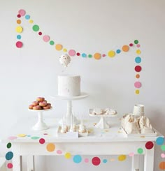 a table topped with cake and cupcakes next to a wall covered in confetti