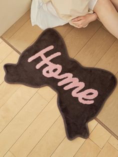 a woman sitting on the floor with her feet up next to a rug that says home