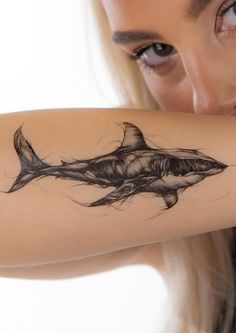 a woman with a tattoo on her arm holding onto a piece of art that looks like a shark