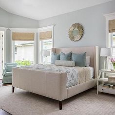 a bedroom with blue and white decor, including a bed in the center surrounded by two chairs