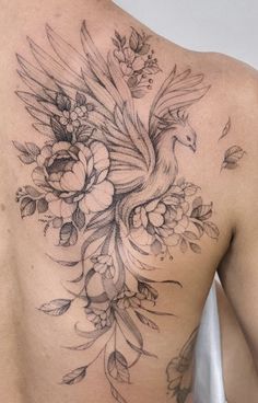 the back of a woman's shoulder with flowers and a bird tattoo on it