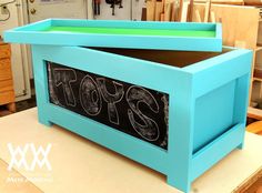 a blue box with the word toys written in chalk on it sitting on top of a table