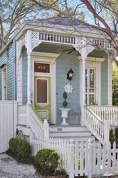 a blue house with white picket fence around it and a light on the front door