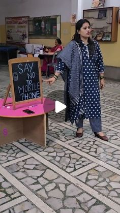 a woman standing in front of a sign that says say no to mobile phones