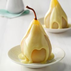 two pears are sitting on a plate covered in icing and drizzle