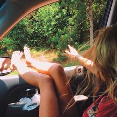 two people sitting in the passenger seat of a car with their feet up on the dashboard