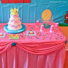 a pink table topped with a cake covered in frosting