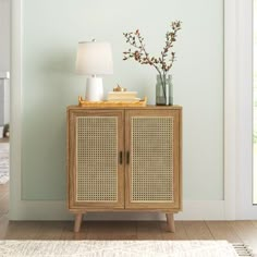 a wooden cabinet with two doors and a lamp on top of it next to a rug