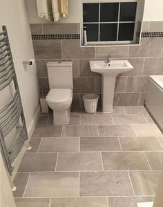 a white toilet sitting next to a sink in a bathroom under a window with a radiator