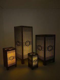 three lit up lanterns sitting next to each other on a white surface in front of a wall