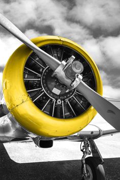 an old propeller airplane sitting on top of a tarmac with clouds in the background