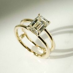 an engagement ring with a princess cut diamond set in yellow gold, on a white background