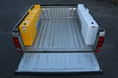 the back end of a pickup truck with two yellow and white containers in the bed