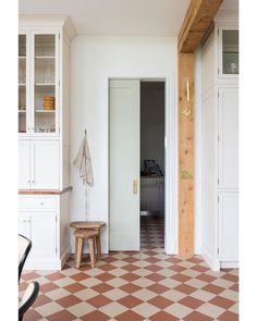 a kitchen with white cabinets and checkered flooring