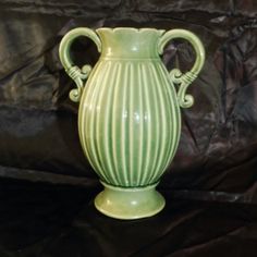 a green vase sitting on top of a black table