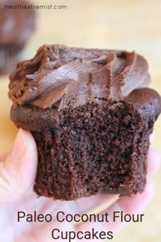 a hand holding a chocolate cupcake with the words paleo coconut flour cupcakes