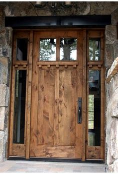 a large wooden door with two sidelights on the front of a stone building,