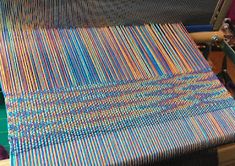 a close up of a weaving machine with colorful yarn on it's back end