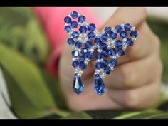 a close up of a person holding a brooch with blue crystals and pearls on it