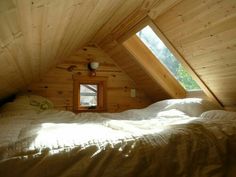 an attic bedroom with wooden walls and white bedding