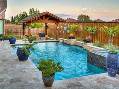 a backyard with a swimming pool surrounded by plants and potted trees in the center