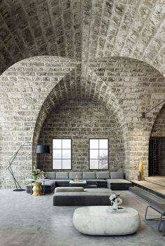 a living room filled with lots of furniture and walls covered in stone arches that look like they have been built into the side of a brick wall