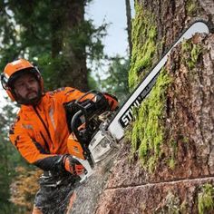 a man in an orange jacket is cutting a tree with a chainsaw