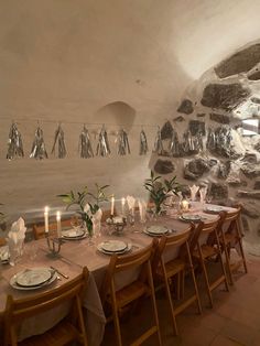 a long table with plates and candles on it in a room that looks like a cave