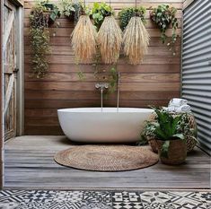 a bathtub with plants hanging from the wall and on the floor next to it